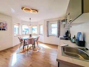 A modern kitchen with a dining area, large windows, and a hanging light fixture. - Bienenwiese by Interhome (Auffach)
