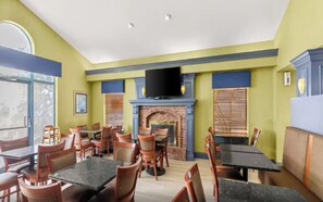 Ein Restaurant mit Tischen, Stühlen, einem Kamin und einem Fernseher.