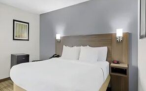 A hotel room with a large bed, bedside tables, a telephone, and a small desk with a lamp. - Cranberry Township Getaway | King Bed & Free Full Breakfast (Cranberry Township)