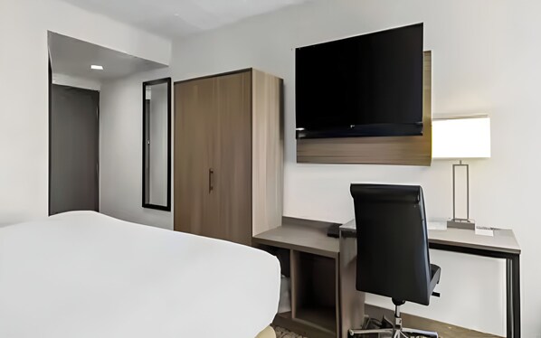 A hotel room with a bed, a desk, a chair, a TV, and a wardrobe. - Cranberry Township Getaway | King Bed & Free Full Breakfast (Cranberry Township)