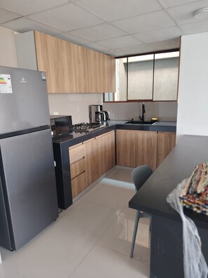 A modern kitchen with a refrigerator, stove, and coffee maker.