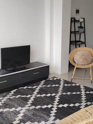 A modern living room with a flat-screen TV on a dark wooden cabinet, a patterned rug, and a wicker chair with a cushion. - 4 bedrooms · View of the Cordillera Blanca · La Soledad (Huaraz)