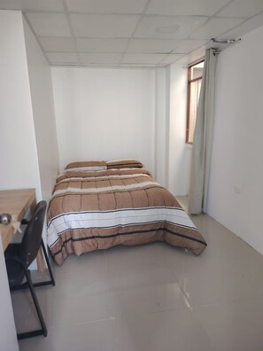 A bedroom with a bed, a desk, and a chair.