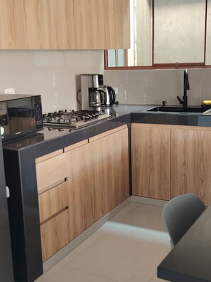 A modern kitchen with wooden cabinets, a gas stove, a microwave, and a coffee maker. - 4 bedrooms · View of the Cordillera Blanca · La Soledad (Huaraz)