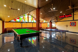 A billiards hall with a pool table, two ping pong tables, and a target on the wall. - Dandeli Serene River Resort (Dandeli)