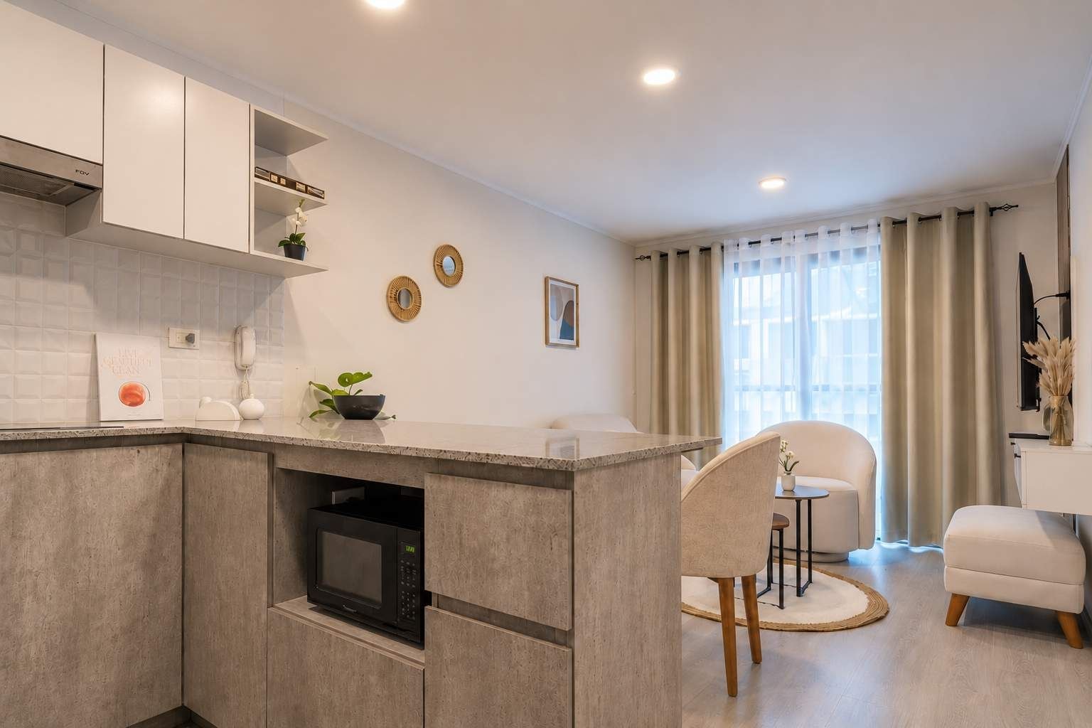 Una cocina moderna con electrodomésticos integrados, un comedor con una silla y una mesa, y un ventanal con cortinas.