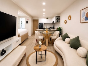 A modern living room with a flat-screen TV, a sofa, a coffee table, and a dining area with chairs. - Moderno Loft en Malecón Piscina Gym (Lima)