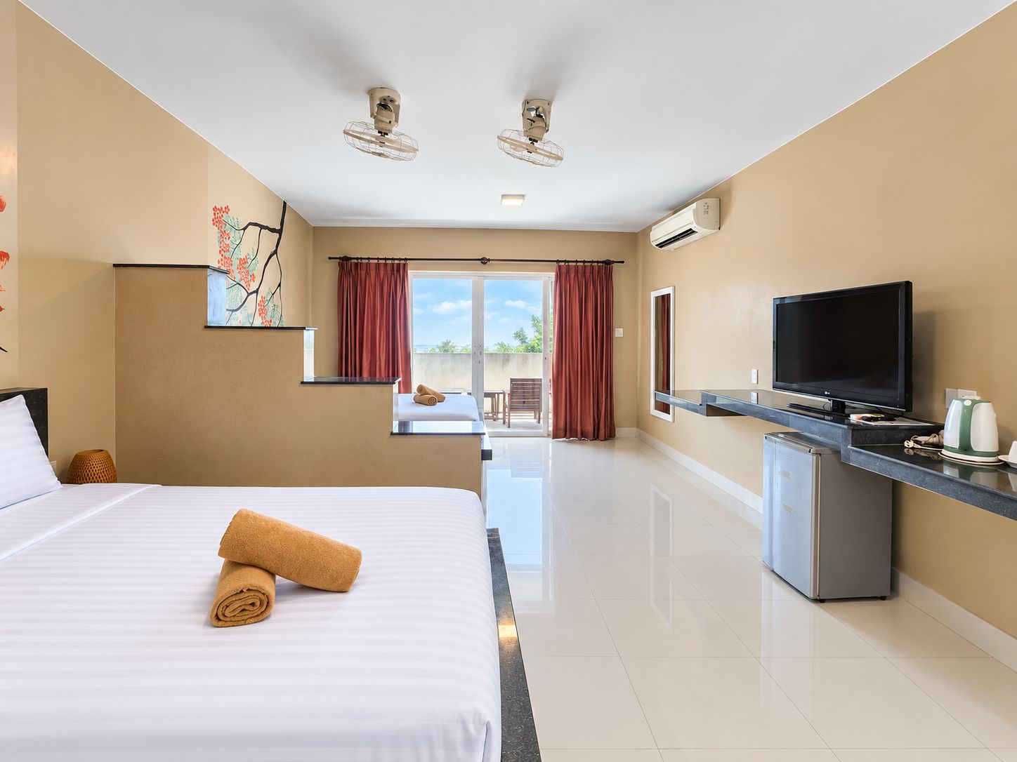 Habitación de hotel con cama, televisión, escritorio y vistas al exterior.