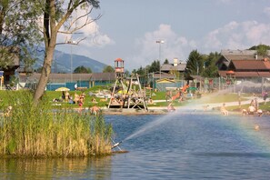 A lakeside recreational area with a wooden play structure, a small dock, and a water fountain. - Apartment With Sauna Near ski Resort (Hollersbach im Pinzgau)