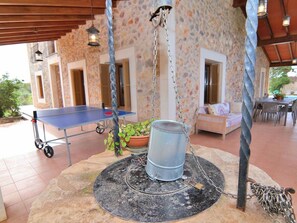 A covered outdoor area with a ping pong table, a hanging metal barrel, and a seating area with a sofa and chairs. - Cabin in Buger With Swimming Pool (Buger)