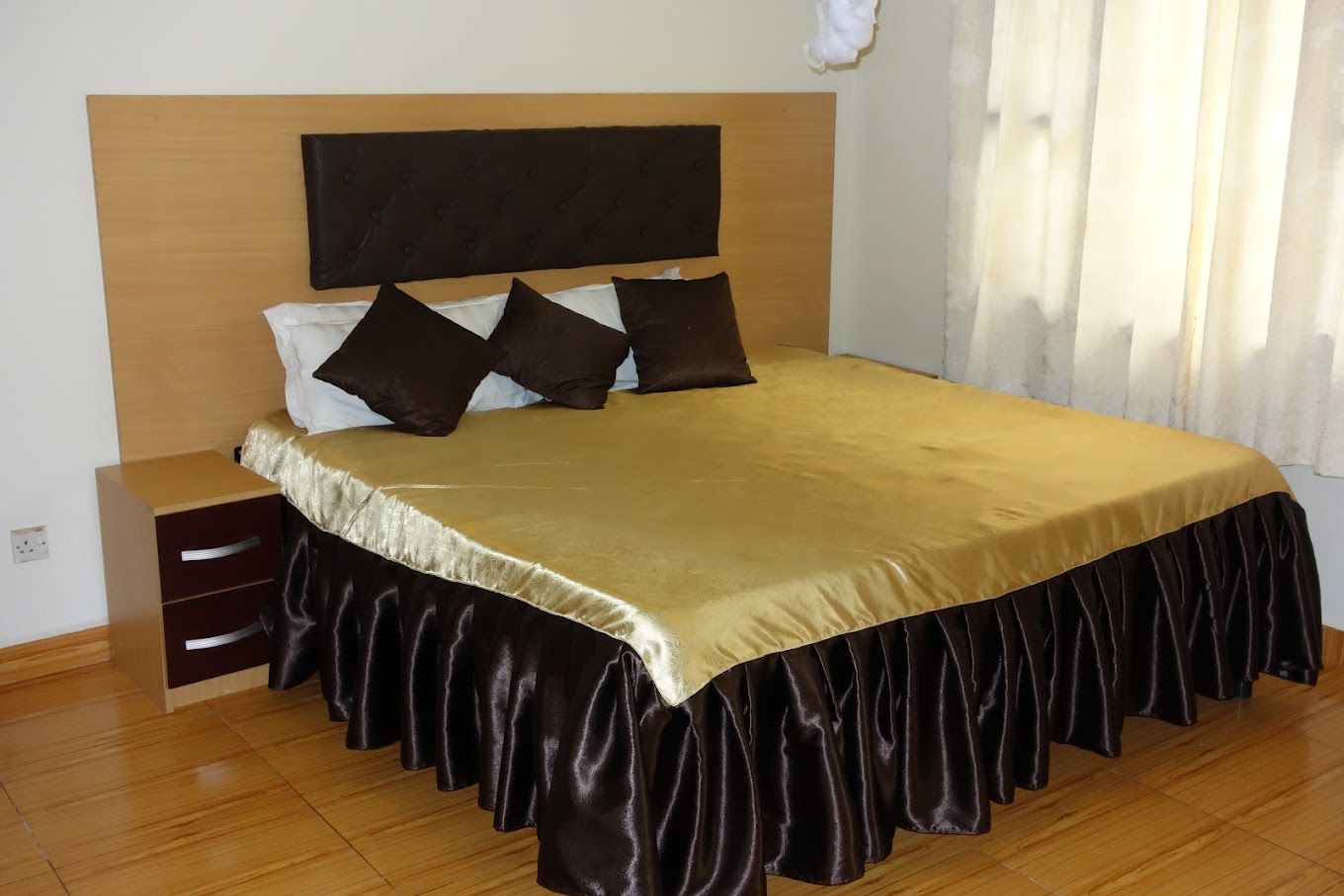 A bedroom with a bed, a nightstand, and a wooden headboard.