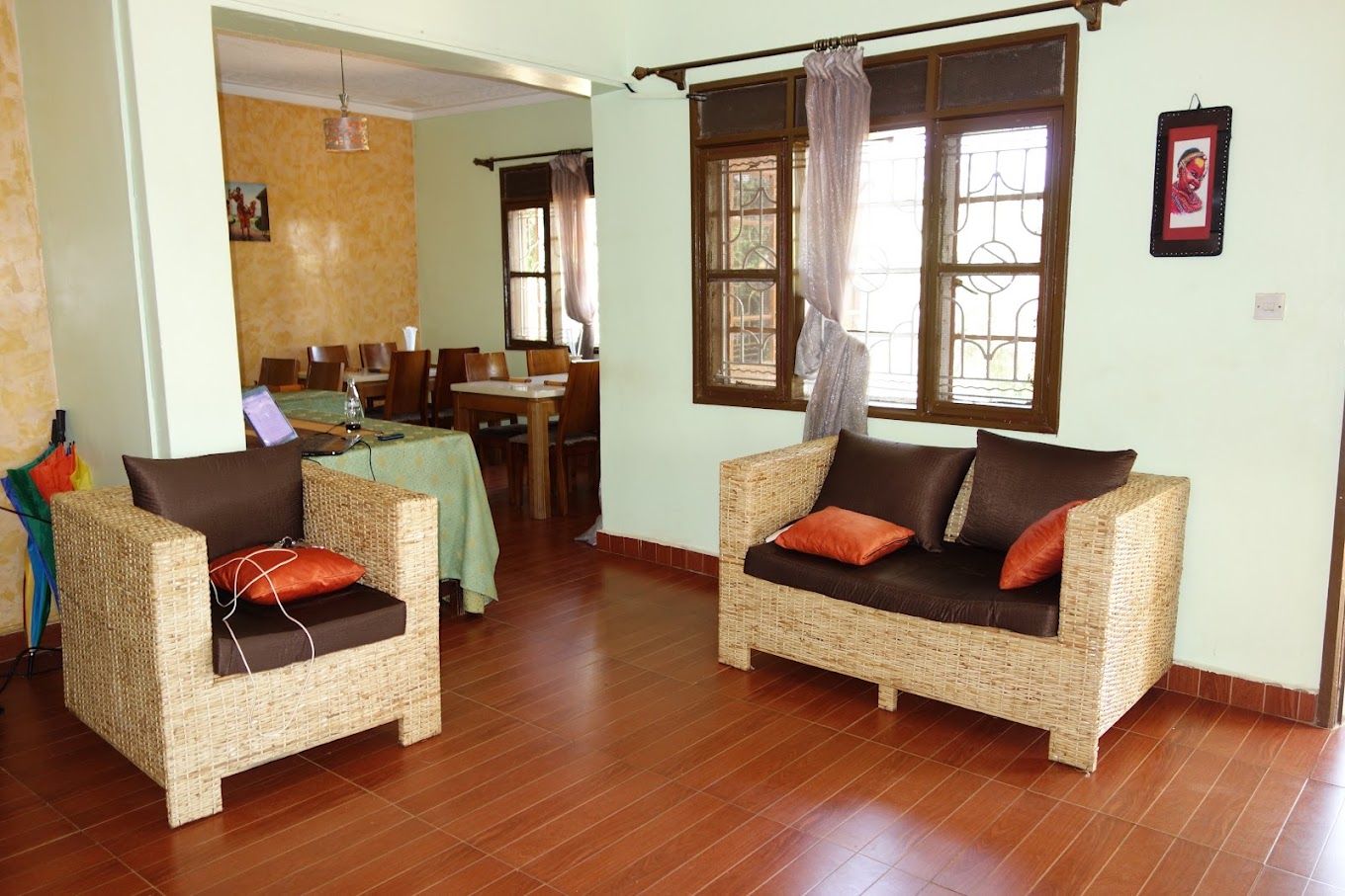 Una habitación con dos sofás de mimbre, una zona de comedor con mesa y sillas, y una ventana con cortinas.