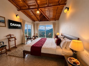 Habitación de hotel con cama, lámparas de noche, televisión y vistas a las montañas.