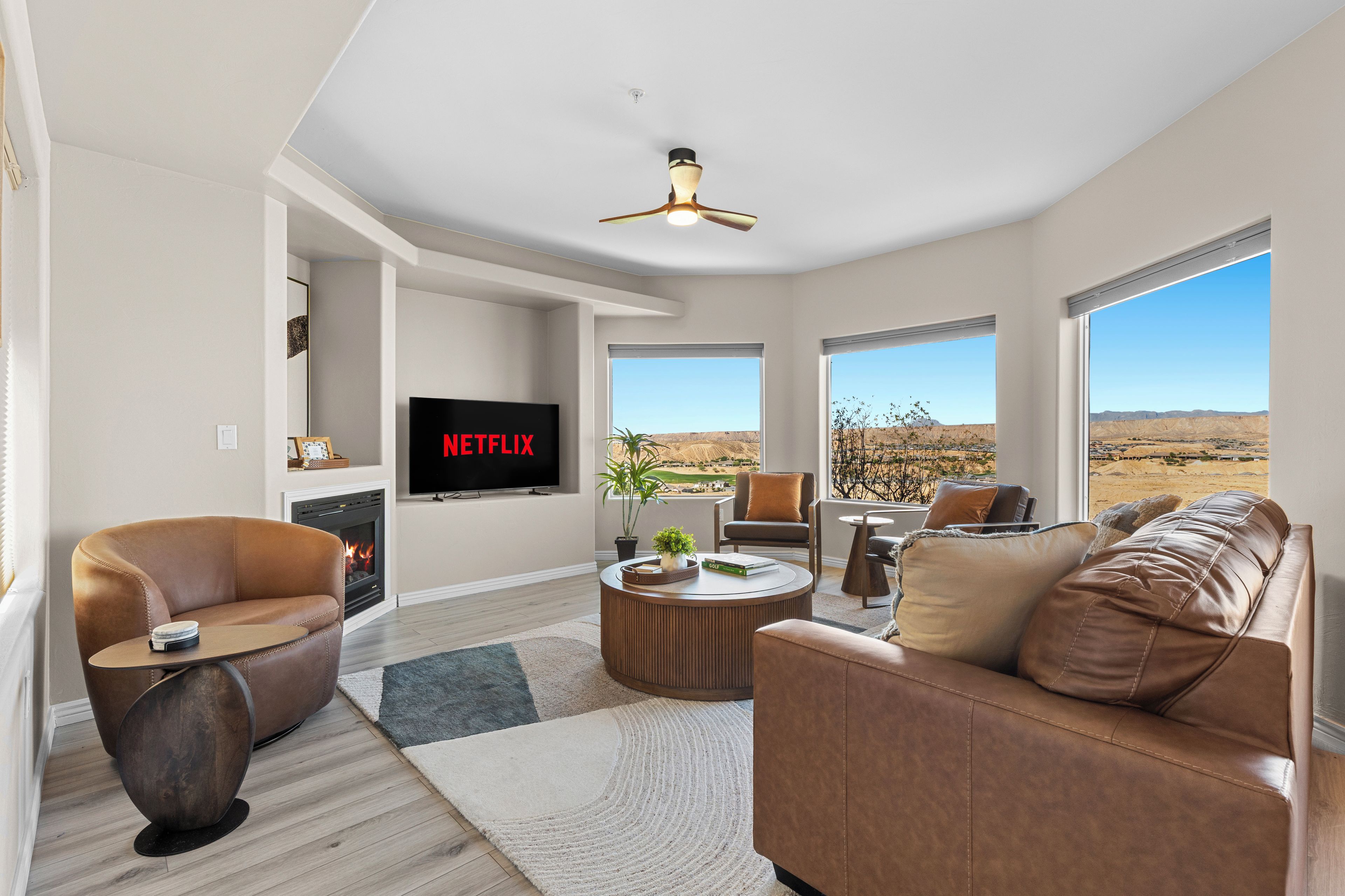 A modern living room with a fireplace, leather sofas, a coffee table, and a TV displaying 'NETFLIX'.