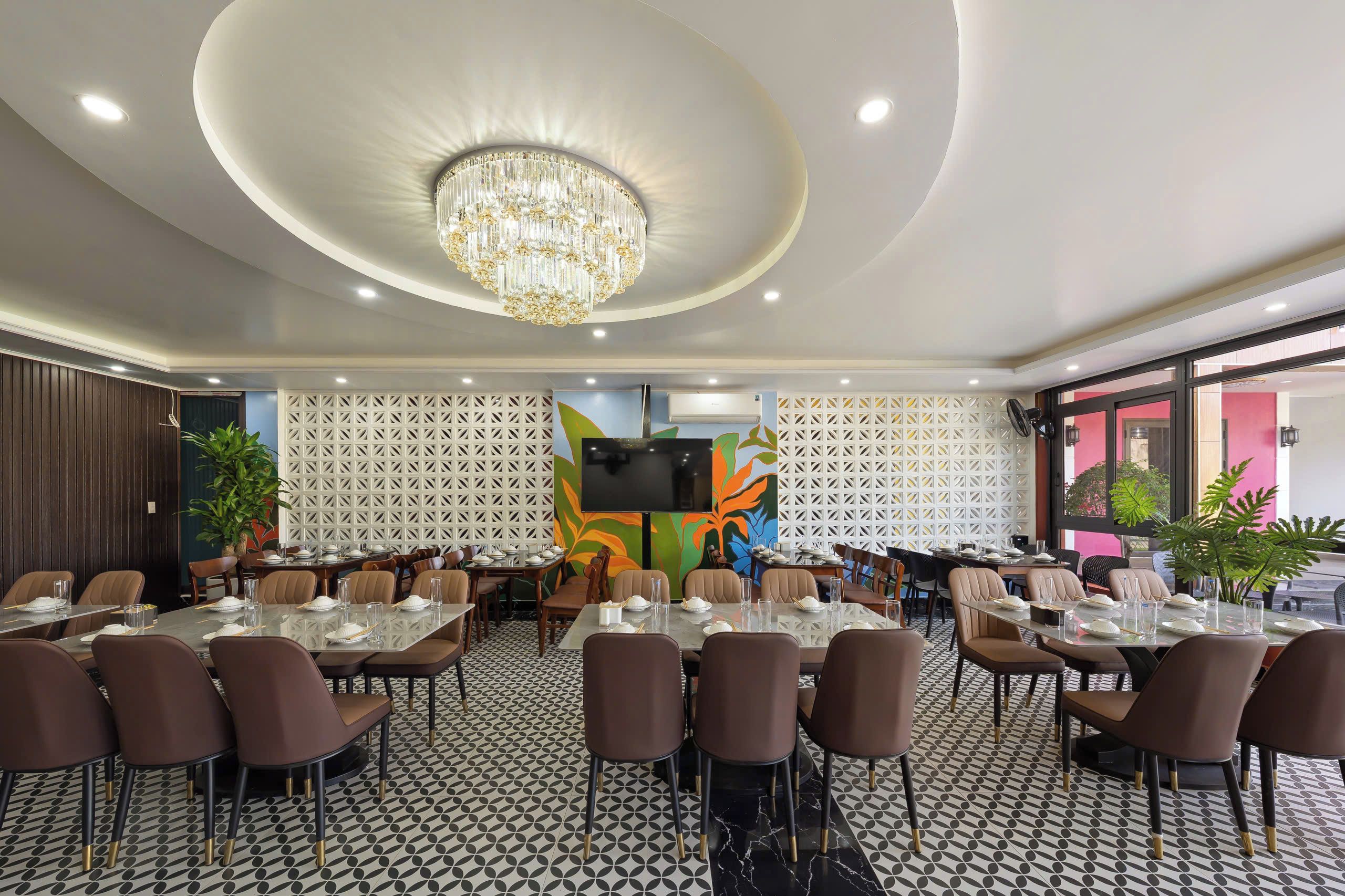 A conference room with round tables, chairs, a chandelier, and a large screen.