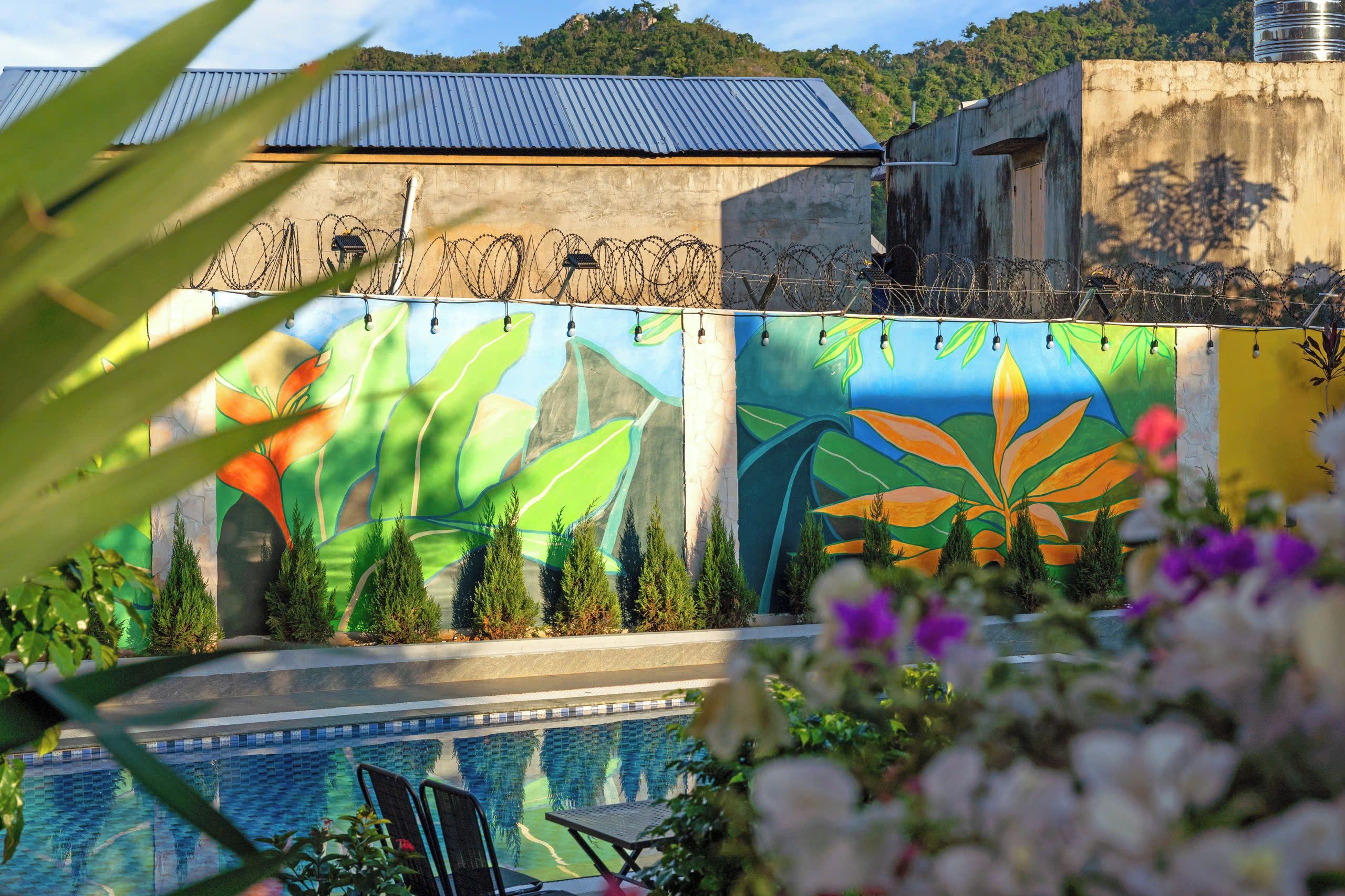 Zona de piscina con un mural, techo de metal y pared de concreto.