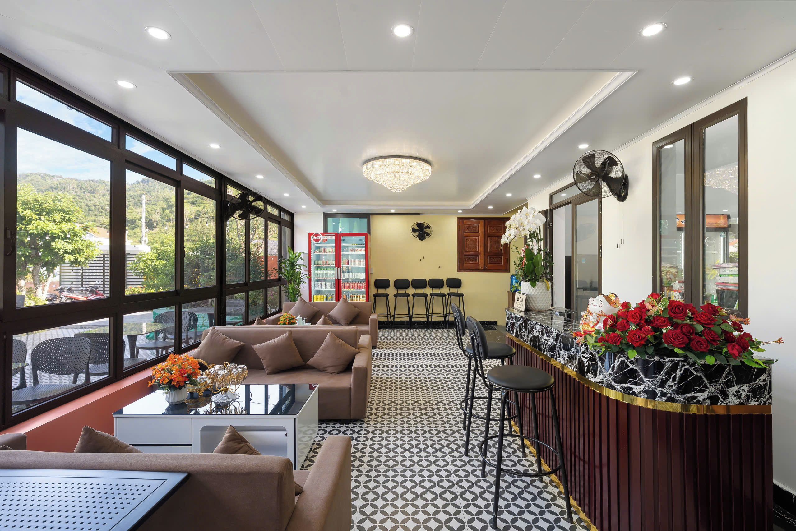 A hotel lobby with a sofa, chairs, a reception desk, and a large window.