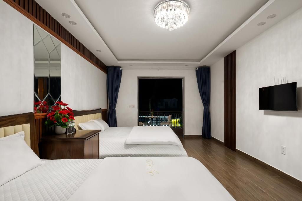 Une chambre d’hôtel avec deux lits, une télévision, un lustre et une vue sur la ville la nuit.