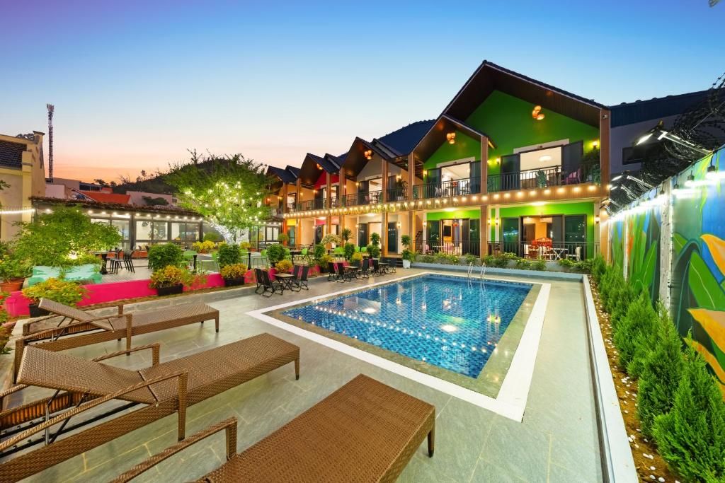 A hotel with a swimming pool, outdoor seating, and a colorful exterior.
