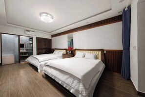 Quarto de hotel com duas camas, piso de madeira, luminária no teto e espelho na parede.