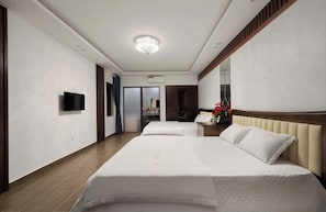 A hotel room with two beds, a television, a mirror, and a view of the bathroom.