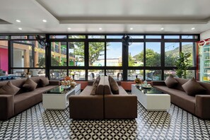 A modern lounge area with a sofa set, a coffee table, and a large window offering a view of the outside.