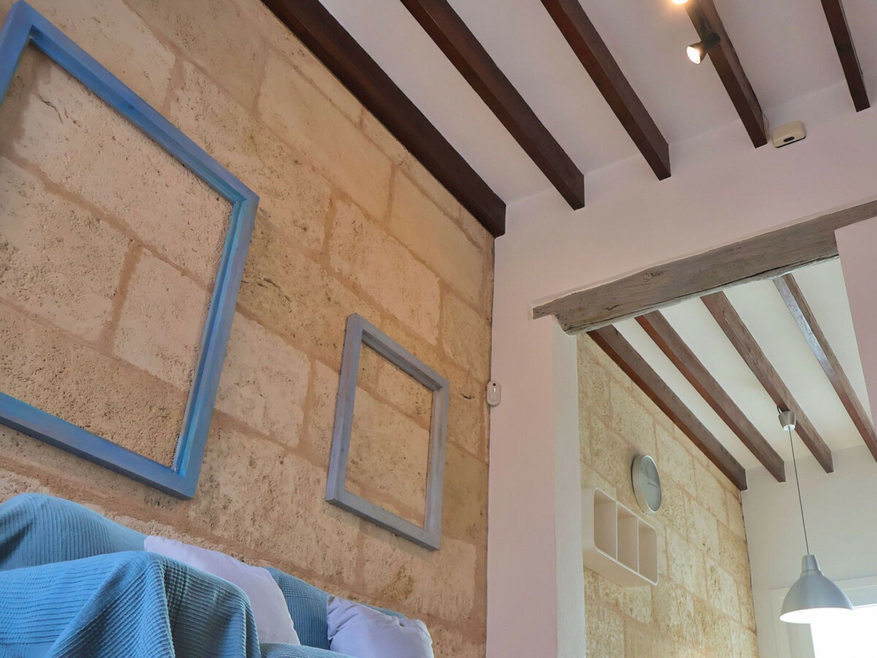 A room with exposed brick walls, wooden beams on the ceiling, and a white door leading to another room.