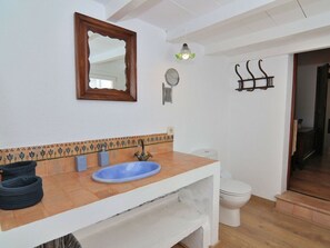 Ein Badezimmer mit einem weißen Waschbecken, einem Spiegel, einer Toilette und einer Duschkabine.