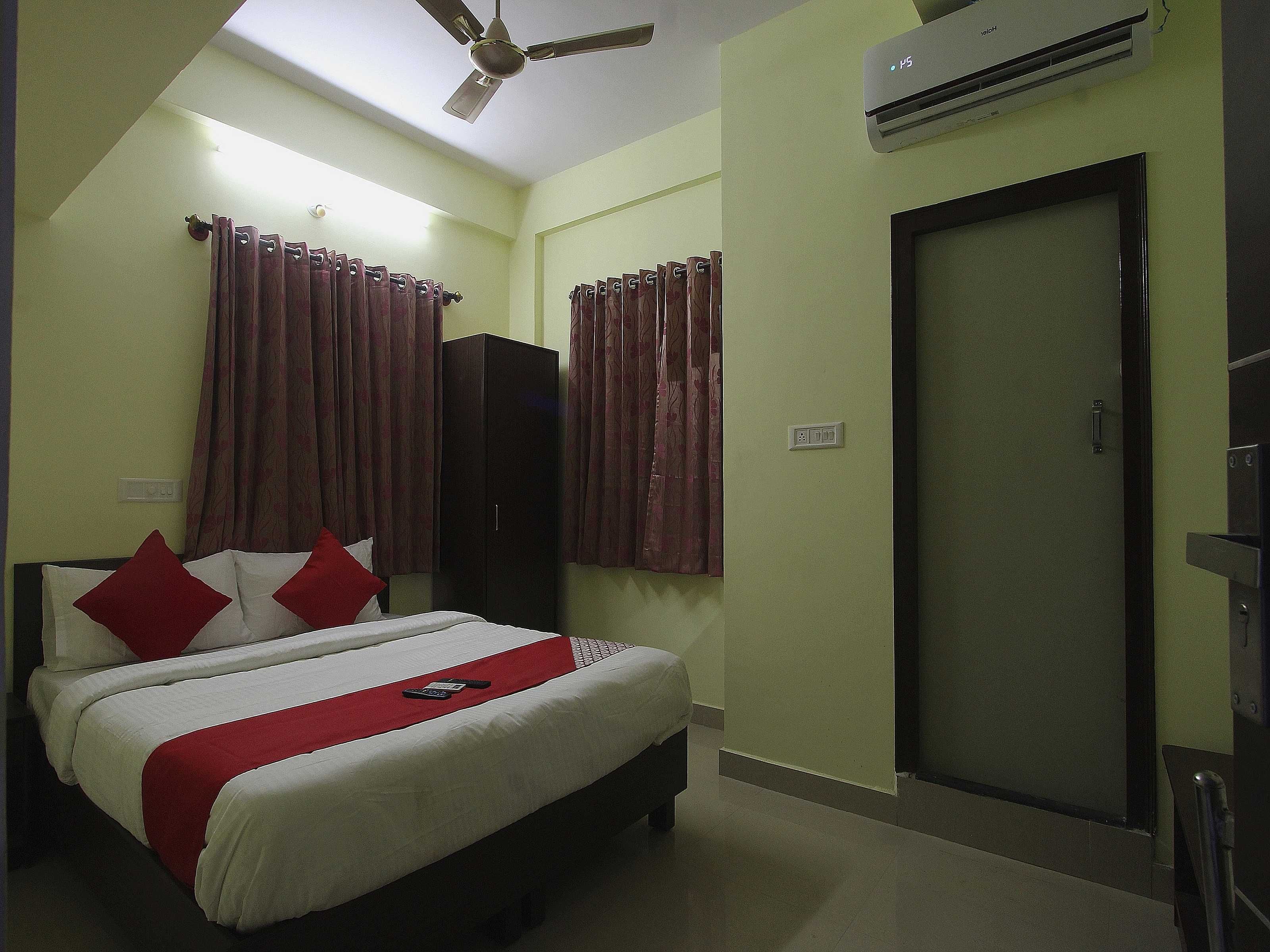 A hotel room with a bed, a wardrobe, a door, and an air conditioning unit.
