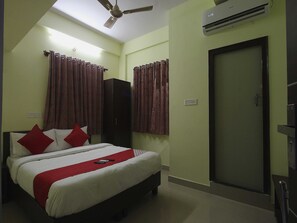 A hotel room with a bed, a wardrobe, a door, and an air conditioning unit. - Hotel O V R Residency Near Sri  (Bangalore)