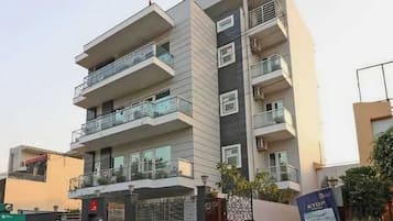 A multi-story residential building with balconies, a gated entrance, and a visible signboard.