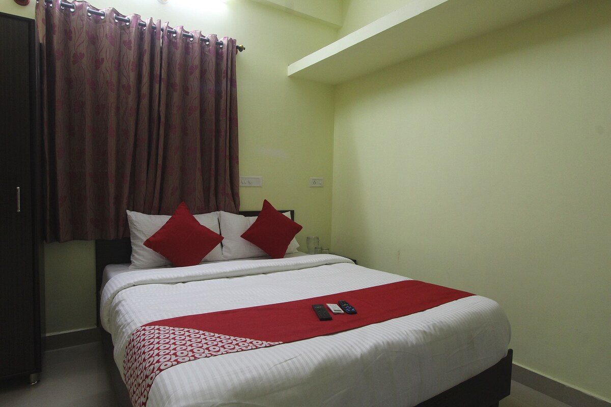 A neatly made bed with white bedding and red accents, a red throw blanket, and a red pillow.