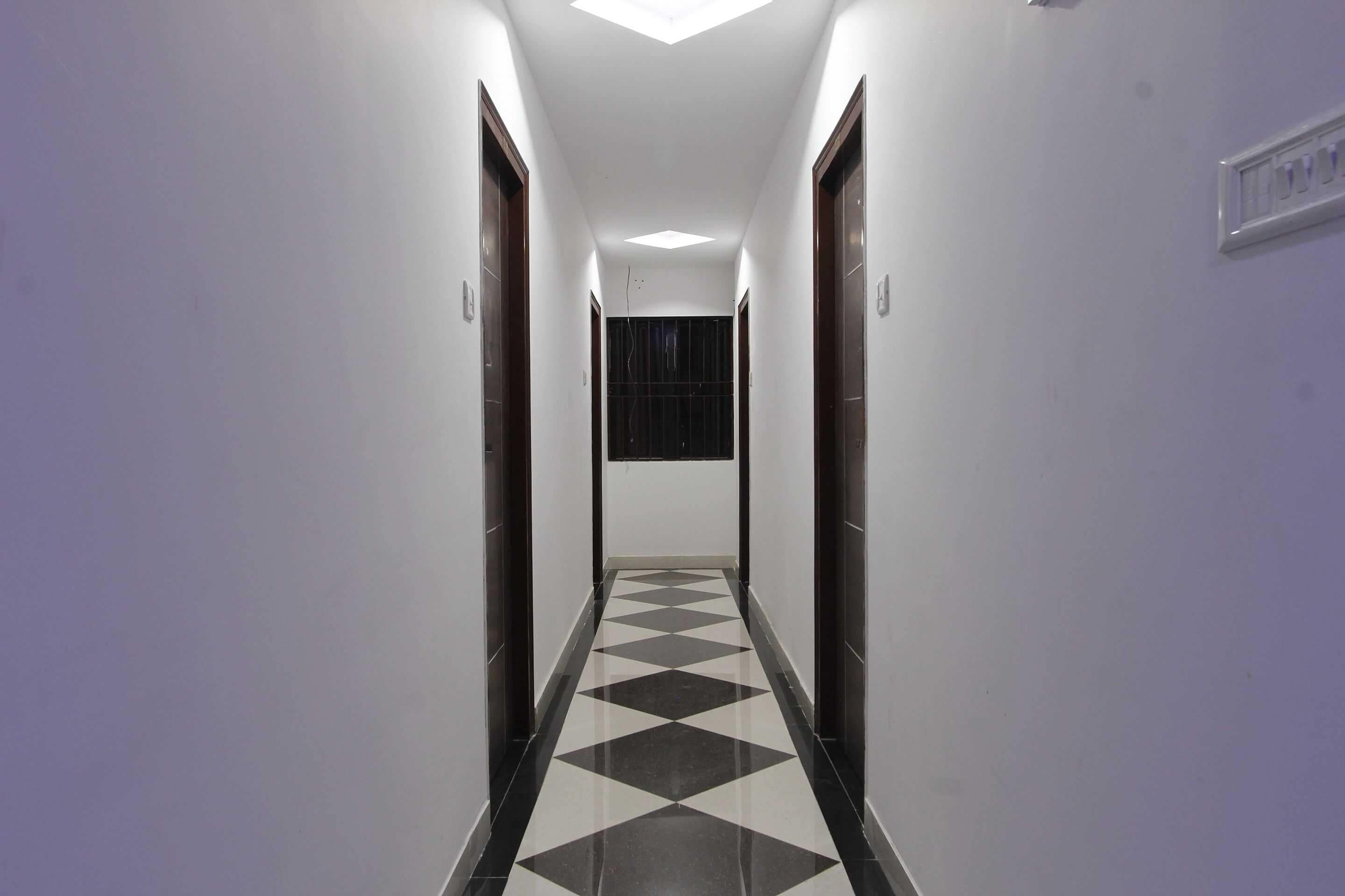 A hallway with a checkered floor pattern, white walls, and doors on both sides.