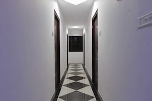 Un pasillo con piso de cuadros, paredes blancas y puertas a ambos lados.