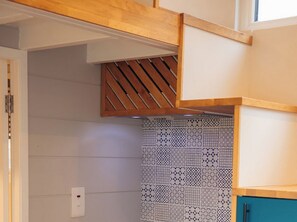 Eine Küche mit Holzbalkendecke, ornamentalem Rücksprühbild und einem blauen Schrank.