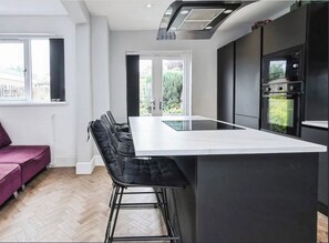 A modern kitchen with a central island, bar stools, and a built-in oven. - 2BR Home with Garden in Selly Oak, Birmingham (Birmingham)
