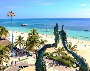 A beach with a statue, palm trees, and a clear blue sea. - King Bed, Fiber-Optic WiFi for Video Calls, Desk, AC, Laundromat Next Door (Playa del Carmen)
