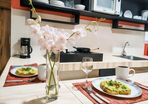 A kitchen with a dining table set for two, featuring avocado toast and a vase of orchids. - Quiet Mornings. Memory Foam King, Kitchen, WiFi AC · 2 Blue Flag Beaches 15 Min (Playa del Carmen)