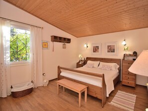 A bedroom with a wooden bed, bedside tables, a bench, a window with curtains, and wall-mounted lights. - 1-bedroom Finca (Santa Margalida)