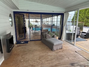 Un espace extérieur aménagé, abrité et doté de meubles de jardin, avec vue sur la piscine, comprenant un canapé et une cheminée.