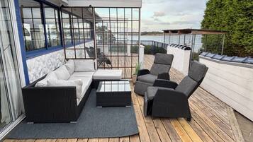 Une terrasse dotée de mobilier d’extérieur, notamment d’un canapé et de fauteuils, et d’une cloison en verre.