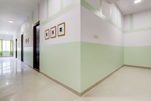 Un pasillo con suelo de baldosas, una puerta y tres cuadros en la pared.