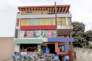 Un edificio de varios pisos con diversos comercios en la planta baja, incluyendo una peluquería y un local de comida.