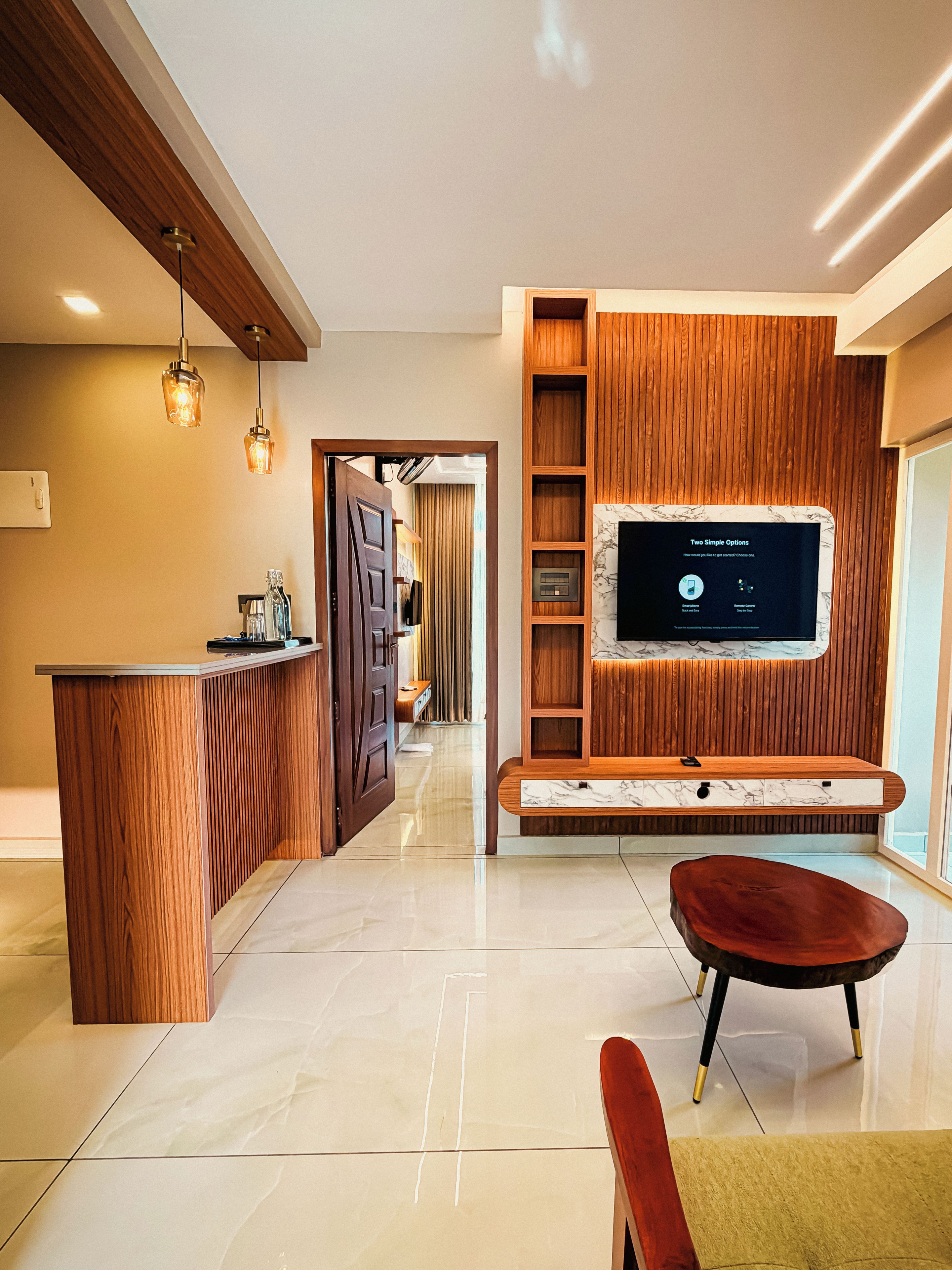 Een moderne woonkamer met een houten entertainmentkast, een flatscreen televisie en een wand bekleed met marmer.