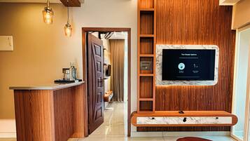 Een moderne woonkamer met een houten entertainmentkast, een flatscreen televisie en een wand bekleed met marmer.