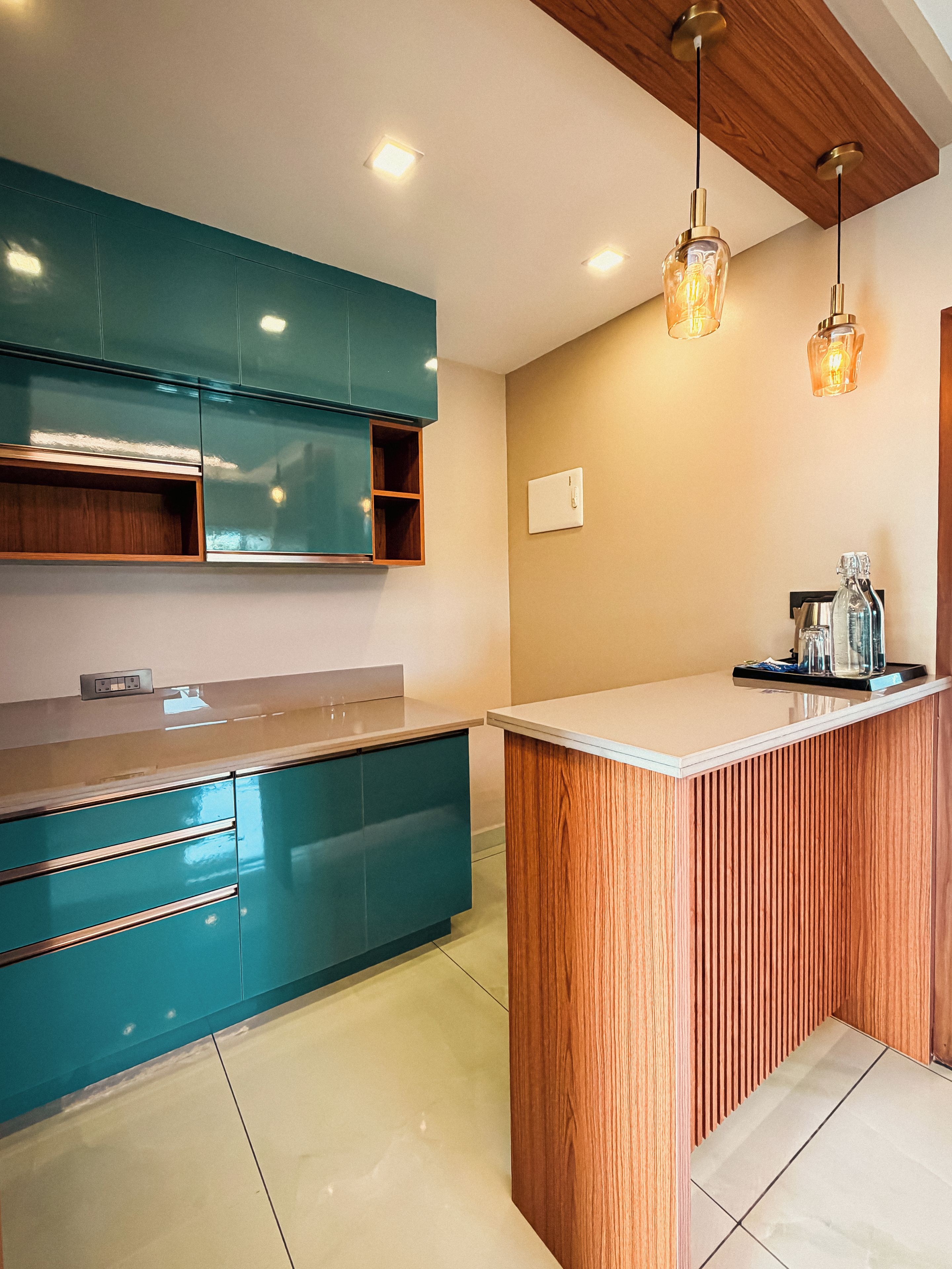 Een moderne keuken met blauwgroene kastjes, een houten eiland en hanglampen.