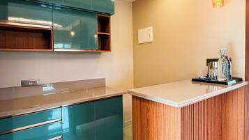 Een moderne keuken met blauwgroene kastjes, een houten eiland en hanglampen.