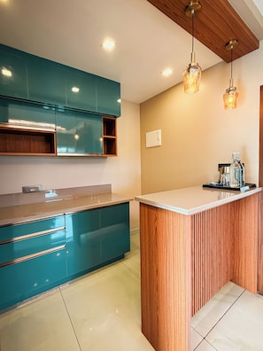 A modern kitchen with teal cabinets, a wooden island, and pendant lighting. - Vaga Castle by Amish Hospitality (Peermade)