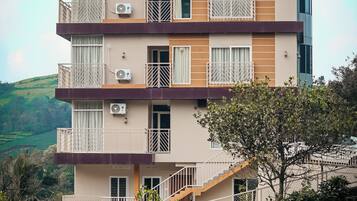 A multi-story building with a sign reading 'Vaga Castle.' It features balconies with railings, air conditioning units, and a staircase leading to the entrance.