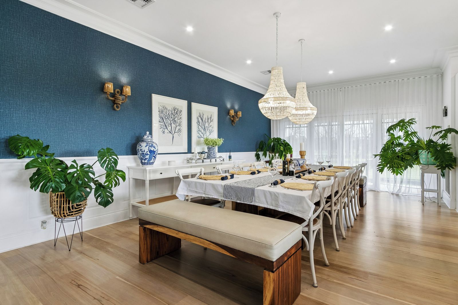Un espace repas avec une longue table dressée pour accueillir plusieurs personnes, un banc et des éléments décoratifs muraux.